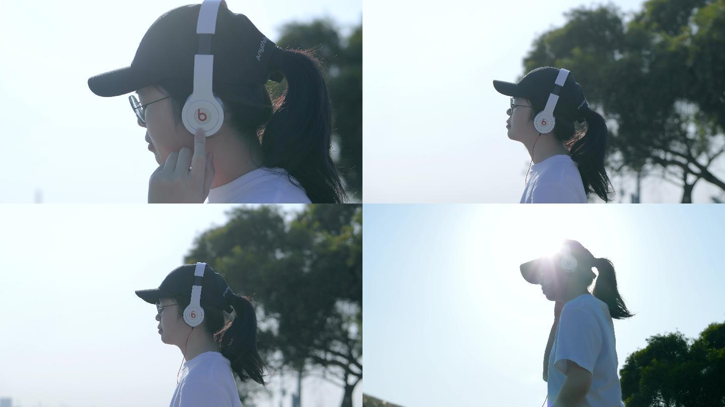 戴着鸭舌帽的女孩在海边用有线耳机听歌