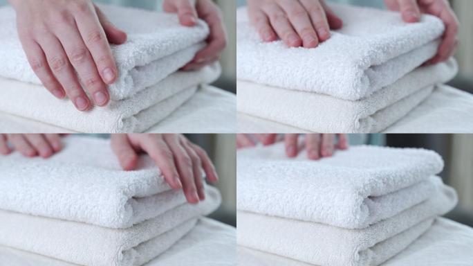 一个女人抚摸折好的白毛巾