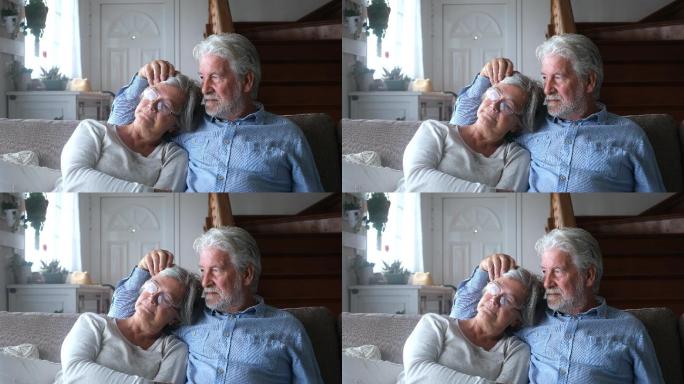 两个悲伤沮丧的老人坐在家里的沙发上