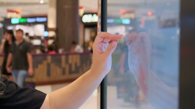 女性在购物中心的数字触摸屏指南上搜索