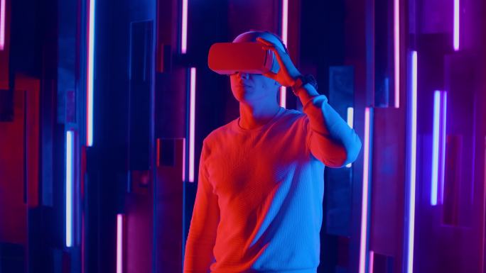 站着的人在霓虹灯下使用VR耳机