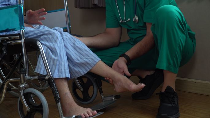 医生在检查坐在轮椅上患者的膝盖