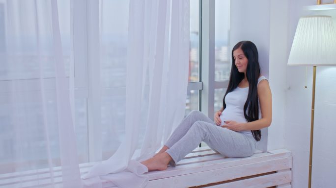 美丽的孕妇坐在窗边