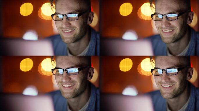 一个帅哥在晚上用笔记本电脑微笑的特写镜头