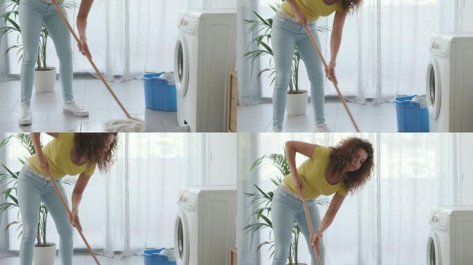 洗衣机坏了，在地板上漏水，女人用拖把清洗