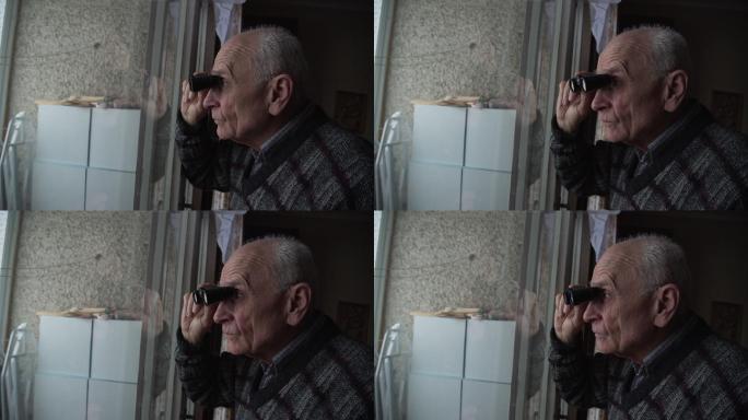 老人拿着黑色双筒望远镜透过窗户看