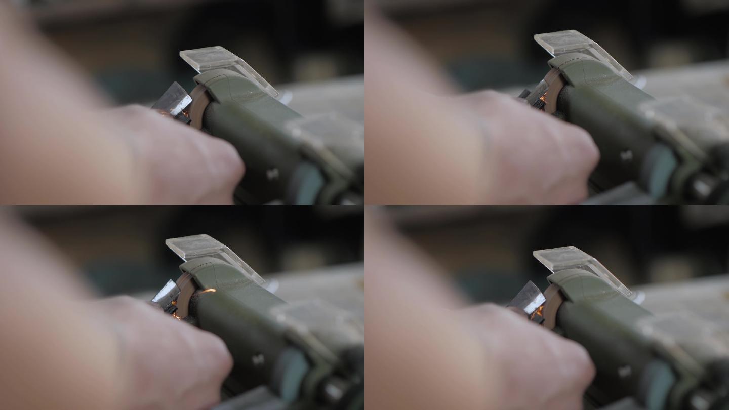 一名工人用电动磨石上的轴承磨自制凿子
