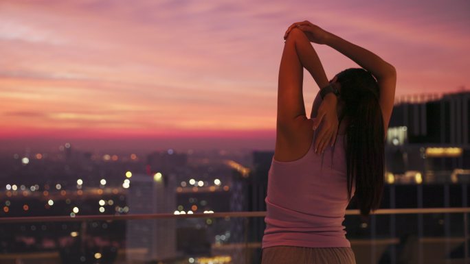 在屋顶露台做瑜伽实拍夜景看城市风光
