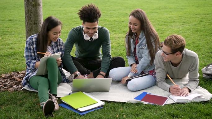 大学生坐在户外的草地上学习