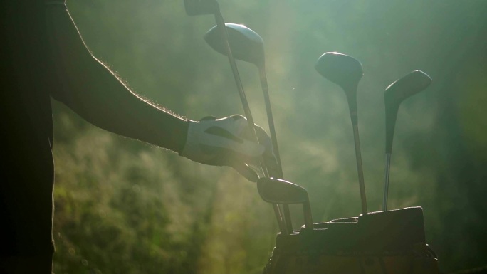 日落时，一只手拿着一个高尔夫球杆