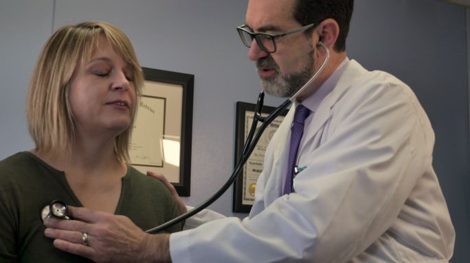 医生用听诊器对女性患者进行肺部检查
