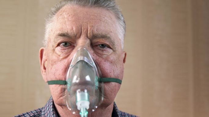 一位戴着氧气面罩的老年人深呼吸