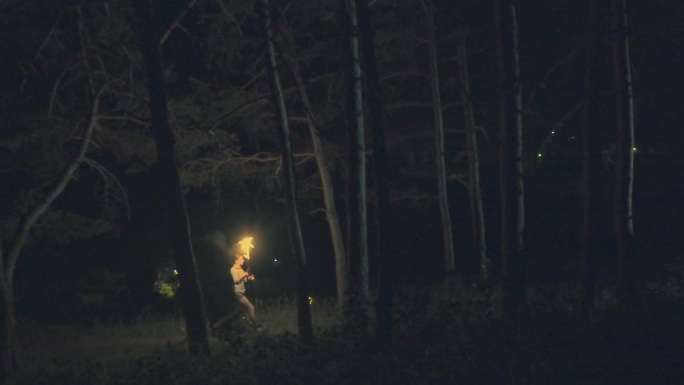 女人手里拿着火把在森林里奔跑