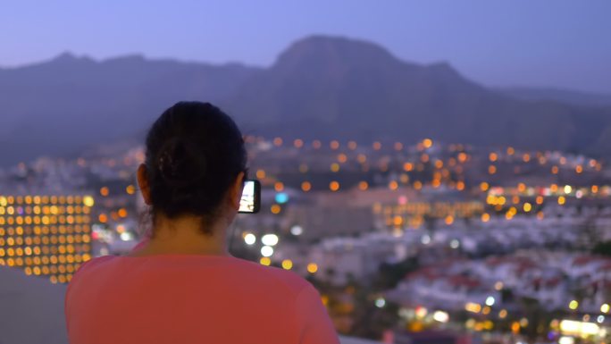 女子在夜间拍摄城市景观灯