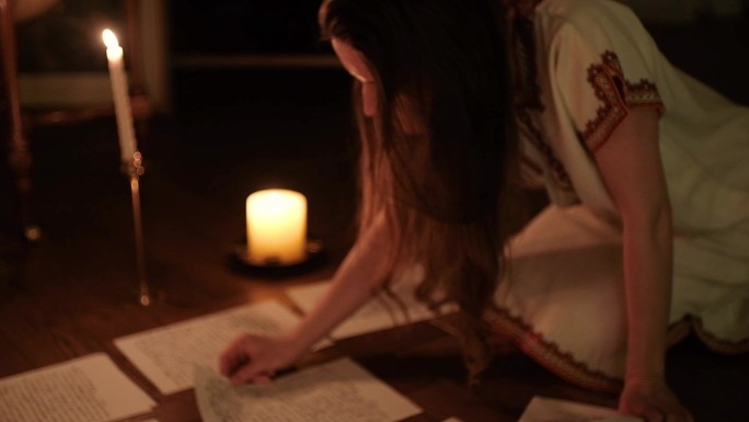 女作家在一间烛光昏暗的房间里写诗