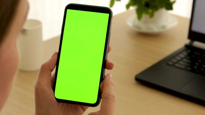 女人拿着一部绿色屏幕的手机