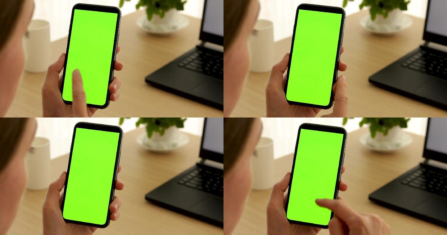 女人拿着一部绿色屏幕的手机