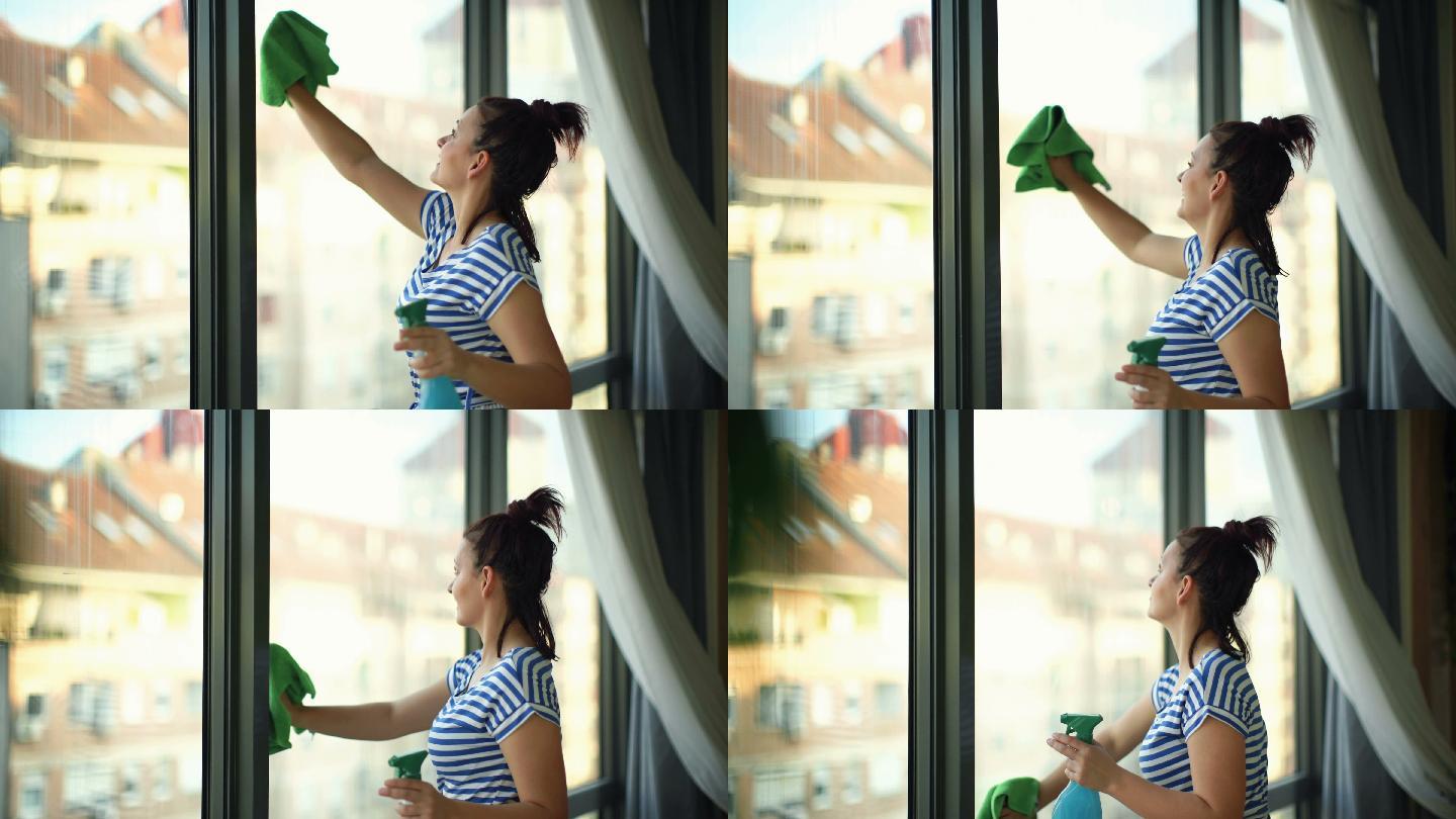 使用喷雾和超细纤维布清洁窗户的女性