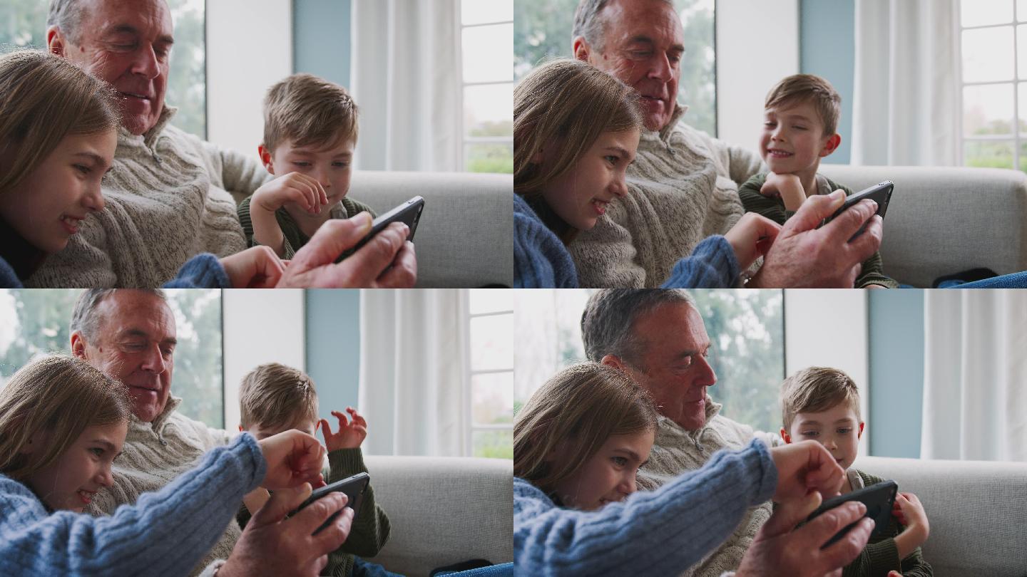 祖父在家里用手机和孙子孙女玩电子游戏
