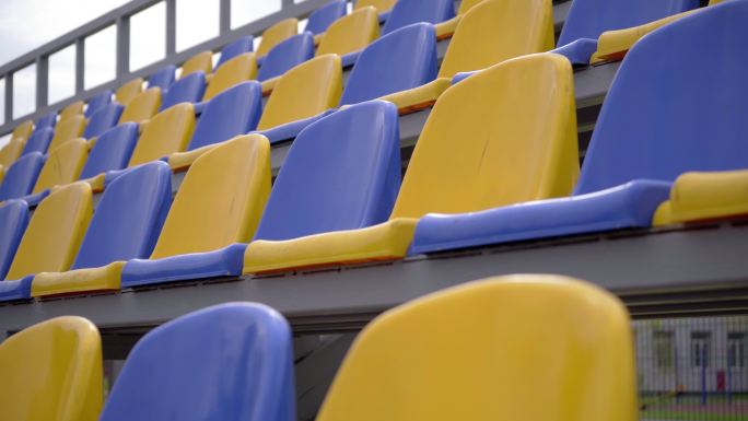 一排排黄色和蓝色的塑料座椅在体育场上