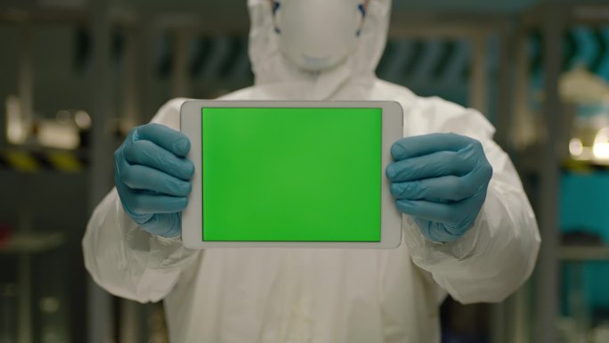 研究人员站在实验室里，手持绿屏平板电脑