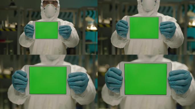 研究人员站在实验室里，手持绿屏平板电脑