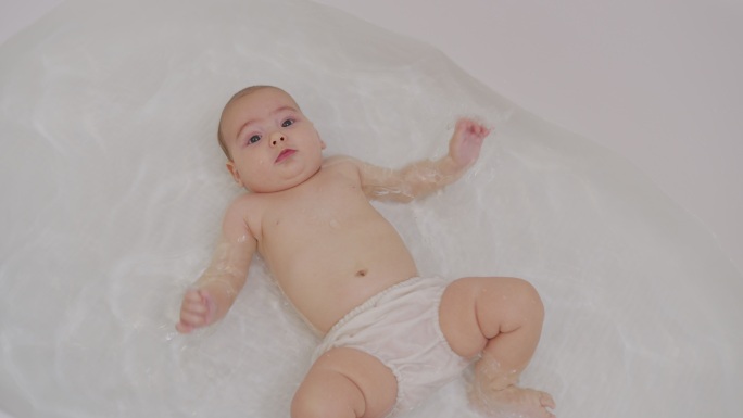 有趣的新生儿在洗澡时游泳