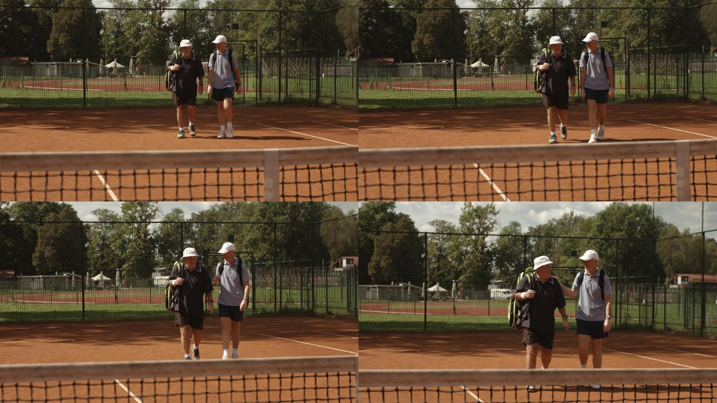 两位老人走在网球场上准备打球