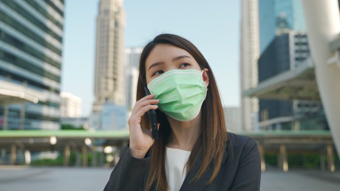 女商人戴着防护口罩在城里打电话