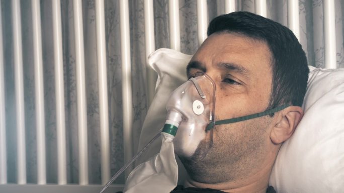 男性由于呼吸困难，他戴着氧气面罩。
