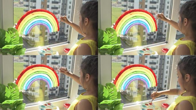 在家隔离期间，女孩在窗户上画彩虹。