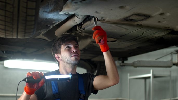修理工修理汽车车底拧螺丝外国人修车