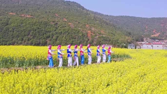 春天在油菜花海载歌载舞的少数民族妇女