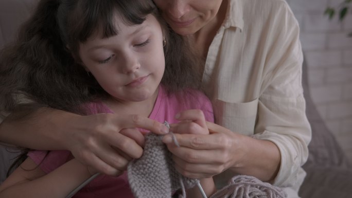 母亲教女儿织毛衣。