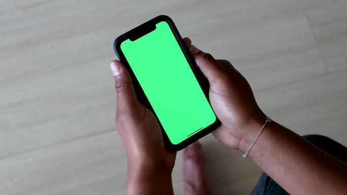 女子手持绿色屏幕手机