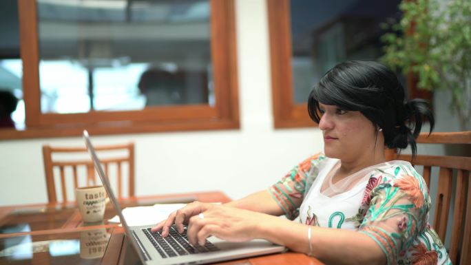 一位矮人妇女在家使用笔记本电脑工作