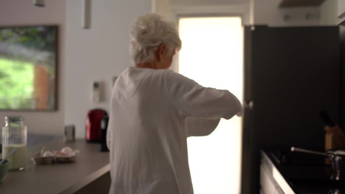 在家里的厨房里做饭跳舞的老妇人