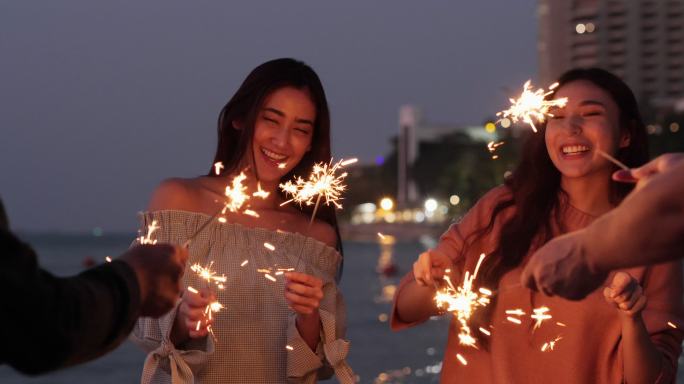 美丽的年轻女子和她的朋友在海边玩起了火花