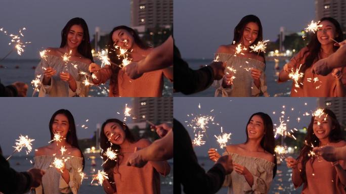 美丽的年轻女子和她的朋友在海边玩起了火花
