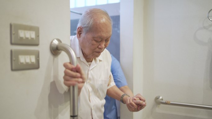 老年男子与护理助理在卫生间使用安全滑扶手