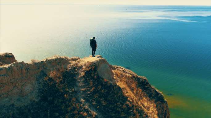 旅行者站在海景背景的山崖上