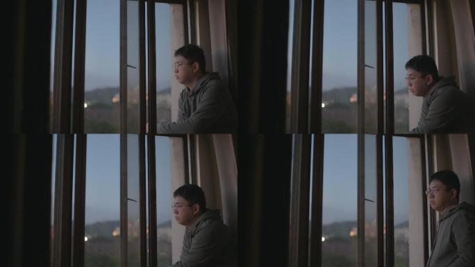日落时分，一名男子从家中望向窗外