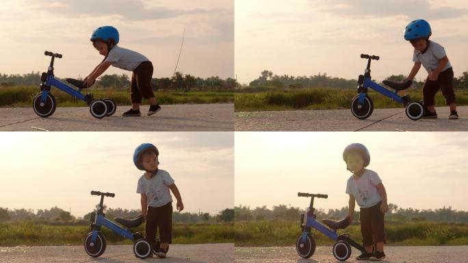 小男孩在推自行车儿童三轮小车戴头盔小孩