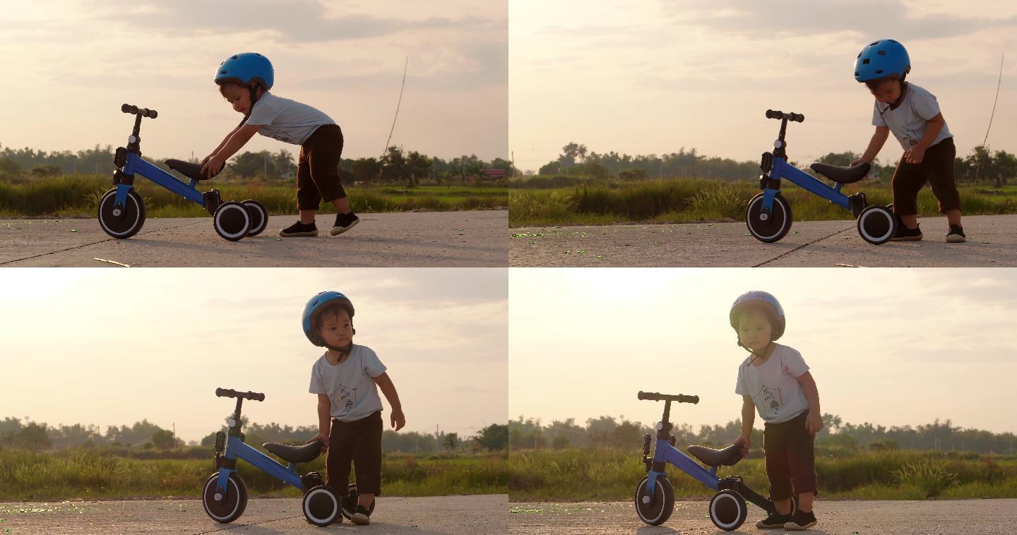 小男孩在推自行车儿童三轮小车戴头盔小孩