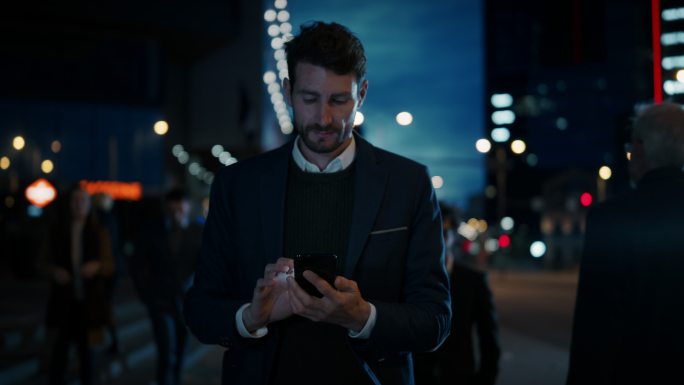商人晚上在黑暗的街道上使用智能手机