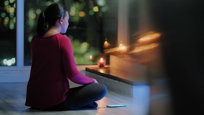 年轻女子晚上在家做瑜伽冥想