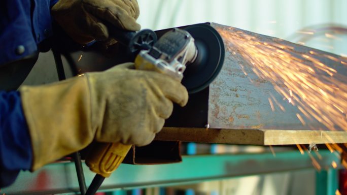 一个金属工人用角磨机切割一块金属。