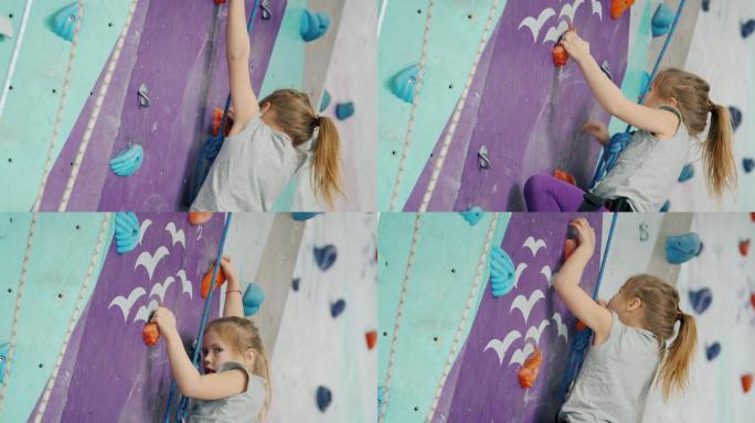 勇敢的孩子小女孩在攀岩馆爬人造墙