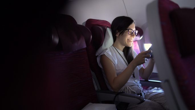 年轻女子正在飞机上用平板电脑