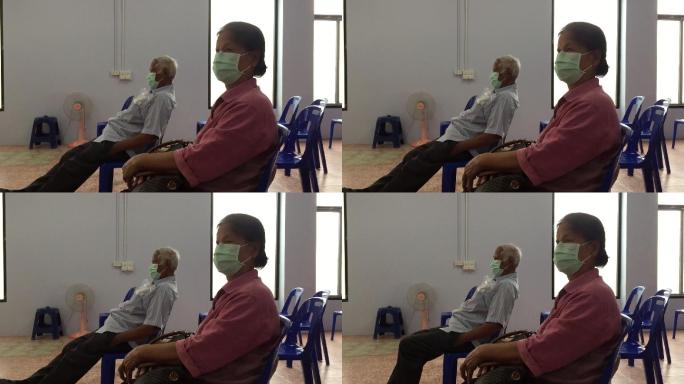 戴着外科口罩的老人坐在医院空荡荡的候诊室